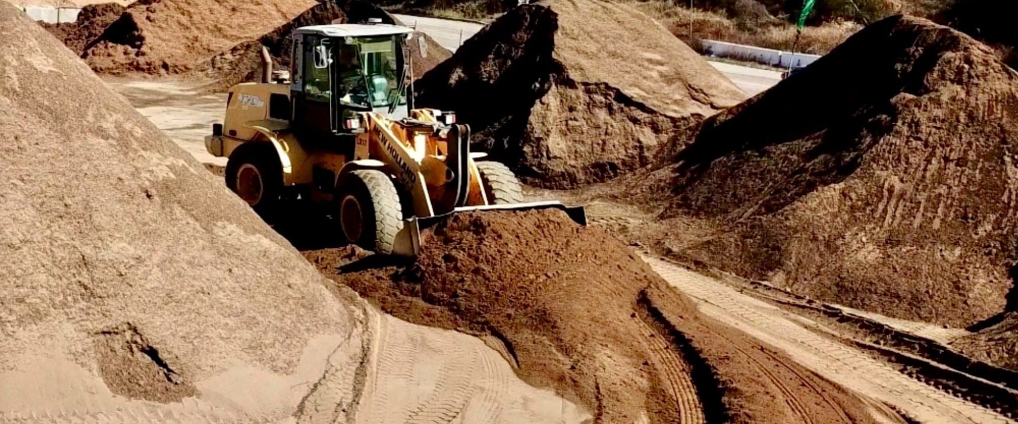 A wheel loader pushing up a pile of screened soil at the yard